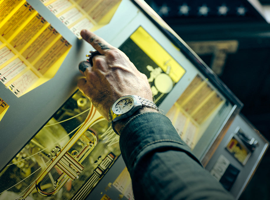 Man picks a song on the jukebox while wearing a Nixon Echo 38 analog watch